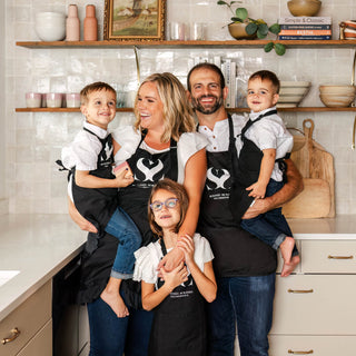 Founder of Blissed Botanical Co, Erin and her family wearing matching aprons and posing in the kitchen