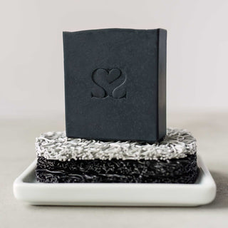 cold process soap bar featured on top two soap lifts on a marble countertop